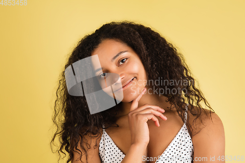 Image of African-american woman portrait isolated on yellow studio background with copyspace