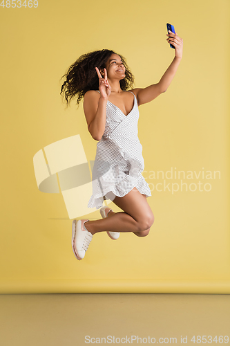 Image of African-american woman portrait isolated on yellow studio background with copyspace