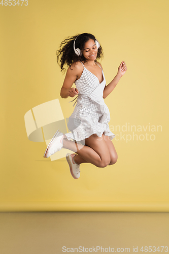 Image of African-american woman portrait isolated on yellow studio background with copyspace