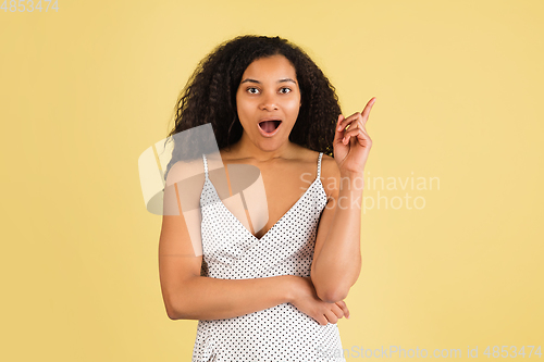 Image of African-american woman portrait isolated on yellow studio background with copyspace