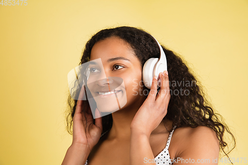 Image of African-american woman portrait isolated on yellow studio background with copyspace