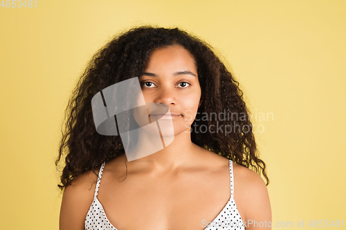 Image of African-american woman portrait isolated on yellow studio background with copyspace