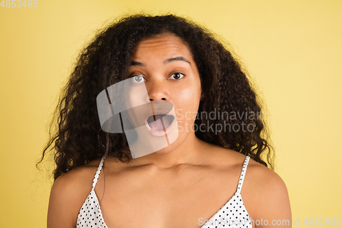 Image of African-american woman portrait isolated on yellow studio background with copyspace