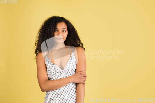 Image of African-american woman portrait isolated on yellow studio background with copyspace