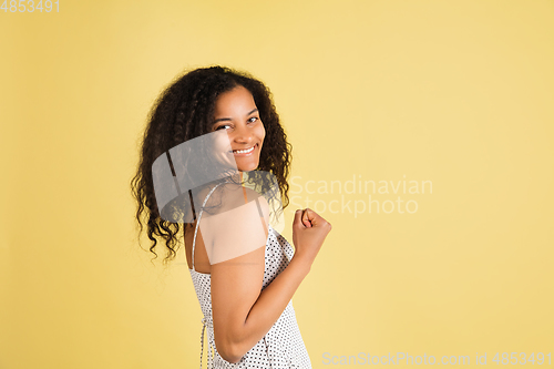 Image of African-american woman portrait isolated on yellow studio background with copyspace