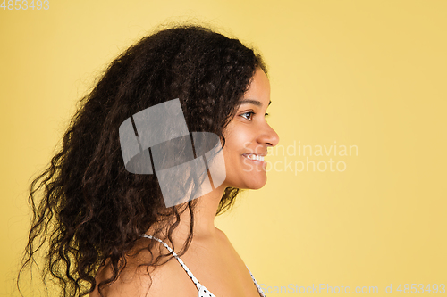 Image of African-american woman portrait isolated on yellow studio background with copyspace