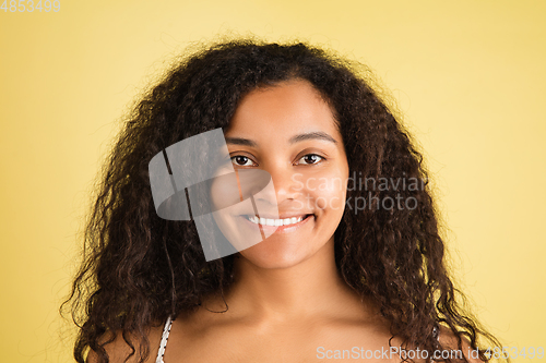 Image of African-american woman portrait isolated on yellow studio background with copyspace