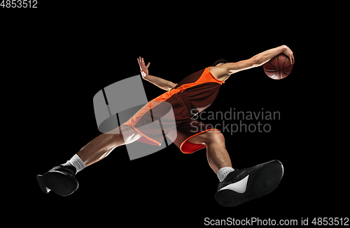 Image of Young professional basketball player in action, motion isolated on black background, look from the bottom. Concept of sport, movement, energy and dynamic.