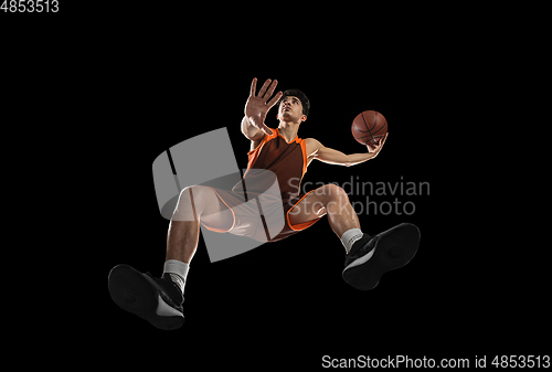 Image of Young professional basketball player in action, motion isolated on black background, look from the bottom. Concept of sport, movement, energy and dynamic.