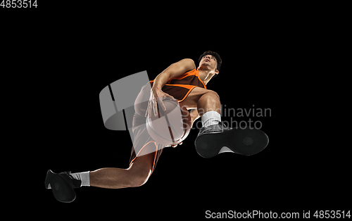Image of Young professional basketball player in action, motion isolated on black background, look from the bottom. Concept of sport, movement, energy and dynamic.