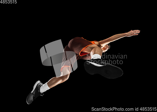 Image of Young professional basketball player in action, motion isolated on black background, look from the bottom. Concept of sport, movement, energy and dynamic.