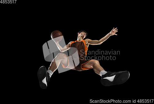 Image of Young professional basketball player in action, motion isolated on black background, look from the bottom. Concept of sport, movement, energy and dynamic.