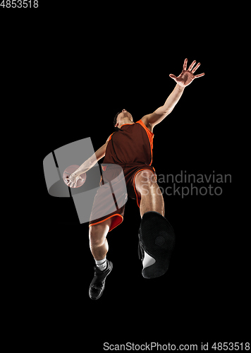 Image of Young professional basketball player in action, motion isolated on black background, look from the bottom. Concept of sport, movement, energy and dynamic.