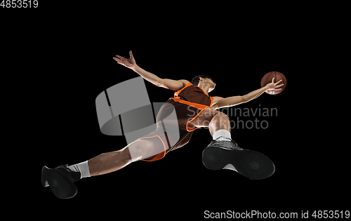 Image of Young professional basketball player in action, motion isolated on black background, look from the bottom. Concept of sport, movement, energy and dynamic.