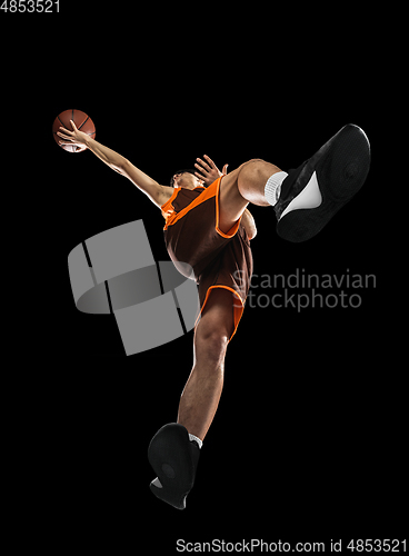 Image of Young professional basketball player in action, motion isolated on black background, look from the bottom. Concept of sport, movement, energy and dynamic.