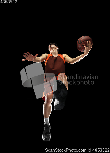 Image of Young professional basketball player in action, motion isolated on black background, look from the bottom. Concept of sport, movement, energy and dynamic.