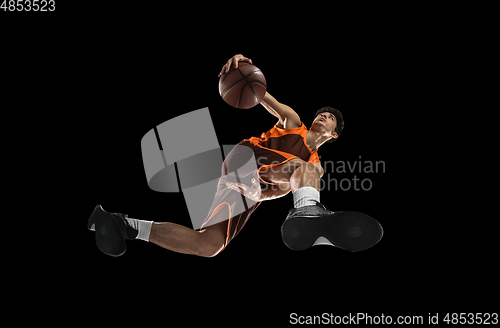 Image of Young professional basketball player in action, motion isolated on black background, look from the bottom. Concept of sport, movement, energy and dynamic.