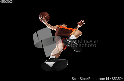 Image of Young professional basketball player in action, motion isolated on black background, look from the bottom. Concept of sport, movement, energy and dynamic.