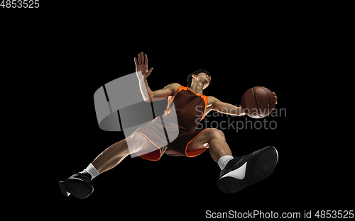 Image of Young professional basketball player in action, motion isolated on black background, look from the bottom. Concept of sport, movement, energy and dynamic.