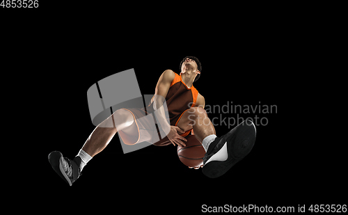 Image of Young professional basketball player in action, motion isolated on black background, look from the bottom. Concept of sport, movement, energy and dynamic.