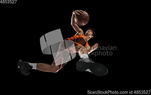 Image of Young professional basketball player in action, motion isolated on black background, look from the bottom. Concept of sport, movement, energy and dynamic.