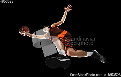 Image of Young professional basketball player in action, motion isolated on black background, look from the bottom. Concept of sport, movement, energy and dynamic.