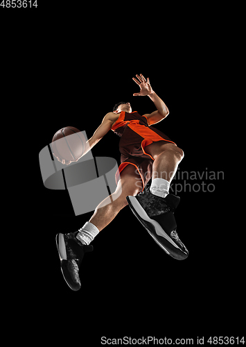 Image of Young professional basketball player in action, motion isolated on black background, look from the bottom. Concept of sport, movement, energy and dynamic.