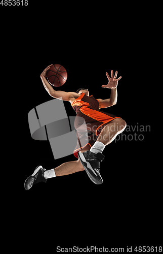 Image of Young professional basketball player in action, motion isolated on black background, look from the bottom. Concept of sport, movement, energy and dynamic.