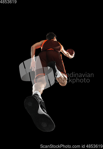 Image of Young professional basketball player in action, motion isolated on black background, look from the bottom. Concept of sport, movement, energy and dynamic.