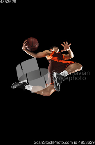 Image of Young professional basketball player in action, motion isolated on black background, look from the bottom. Concept of sport, movement, energy and dynamic.