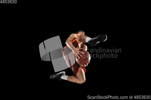 Image of Young professional basketball player in action, motion isolated on black background, look from the bottom. Concept of sport, movement, energy and dynamic.