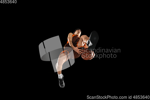 Image of Young professional basketball player in action, motion isolated on black background, look from the bottom. Concept of sport, movement, energy and dynamic.
