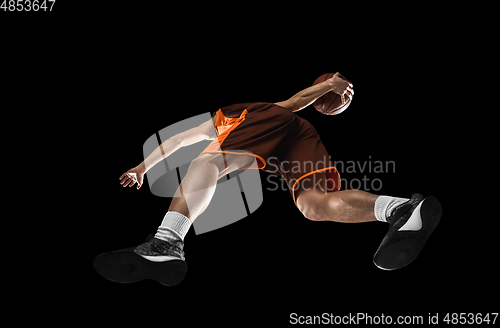 Image of Young professional basketball player in action, motion isolated on black background, look from the bottom. Concept of sport, movement, energy and dynamic.