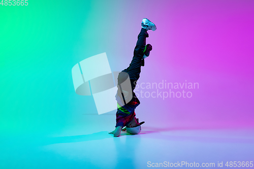 Image of Beautiful sportive boy dancing hip-hop in stylish clothes on colorful gradient background at dance hall in neon light.