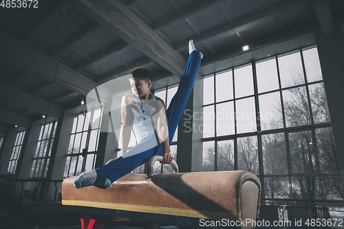 Image of Little male gymnast training in gym, flexible and active. Caucasian fit little boy, athlete in sportswear practicing in exercises for strength, balance.