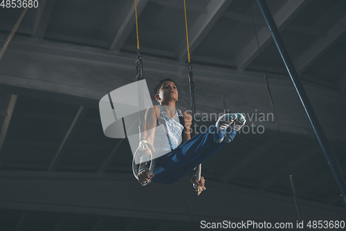 Image of Little male gymnast training in gym, flexible and active. Caucasian fit little boy, athlete in sportswear practicing in exercises for strength, balance.