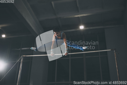 Image of Little male gymnast training in gym, flexible and active. Caucasian fit little boy, athlete in sportswear practicing in exercises for strength, balance.