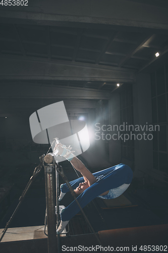 Image of Little male gymnast training in gym, flexible and active. Caucasian fit little boy, athlete in sportswear practicing in exercises for strength, balance.