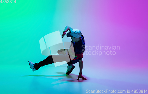 Image of Beautiful sportive boy dancing hip-hop in stylish clothes on colorful gradient background at dance hall in neon light.
