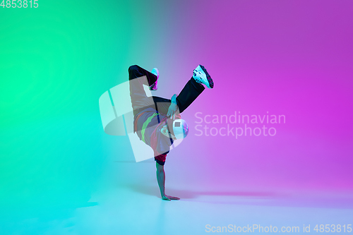 Image of Beautiful sportive boy dancing hip-hop in stylish clothes on colorful gradient background at dance hall in neon light.