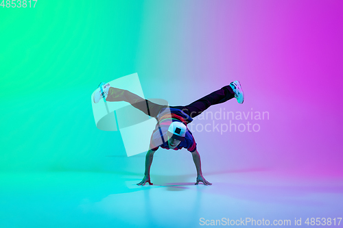 Image of Beautiful sportive boy dancing hip-hop in stylish clothes on colorful gradient background at dance hall in neon light.