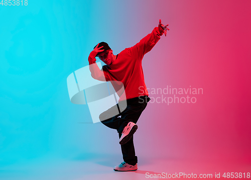 Image of Beautiful sportive boy dancing hip-hop in stylish clothes on colorful gradient background at dance hall in neon light.