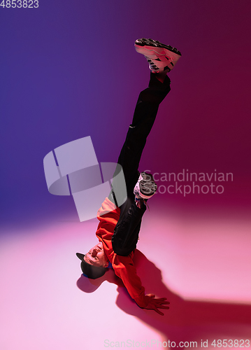 Image of Beautiful sportive boy dancing hip-hop in stylish clothes on colorful gradient background at dance hall in neon light.