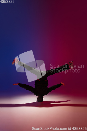 Image of Beautiful sportive boy dancing hip-hop in stylish clothes on colorful gradient background at dance hall in neon light.