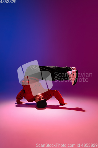 Image of Beautiful sportive boy dancing hip-hop in stylish clothes on colorful gradient background at dance hall in neon light.