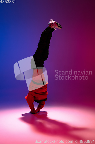 Image of Beautiful sportive boy dancing hip-hop in stylish clothes on colorful gradient background at dance hall in neon light.