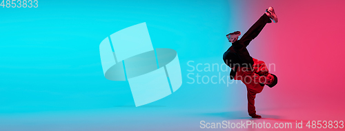 Image of Beautiful sportive boy dancing hip-hop in stylish clothes on colorful gradient background at dance hall in neon light.