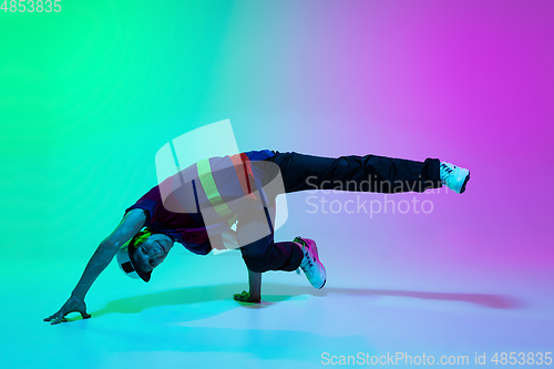 Image of Beautiful sportive boy dancing hip-hop in stylish clothes on colorful gradient background at dance hall in neon light.