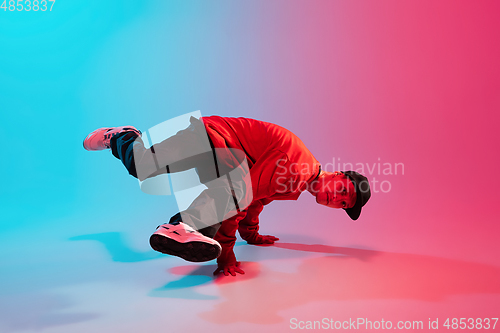 Image of Beautiful sportive boy dancing hip-hop in stylish clothes on colorful gradient background at dance hall in neon light.