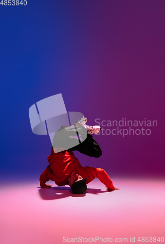 Image of Beautiful sportive boy dancing hip-hop in stylish clothes on colorful gradient background at dance hall in neon light.